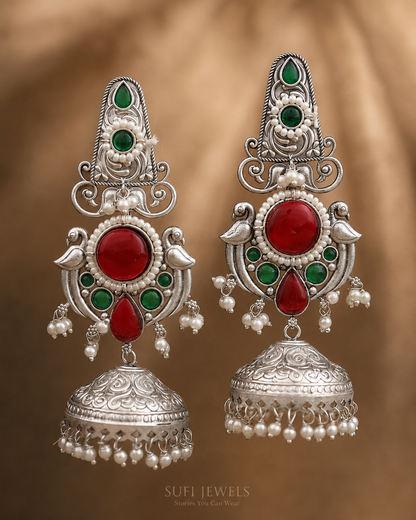 The Garden Between Wings silver look-alike jhumki earrings with red and green stones.