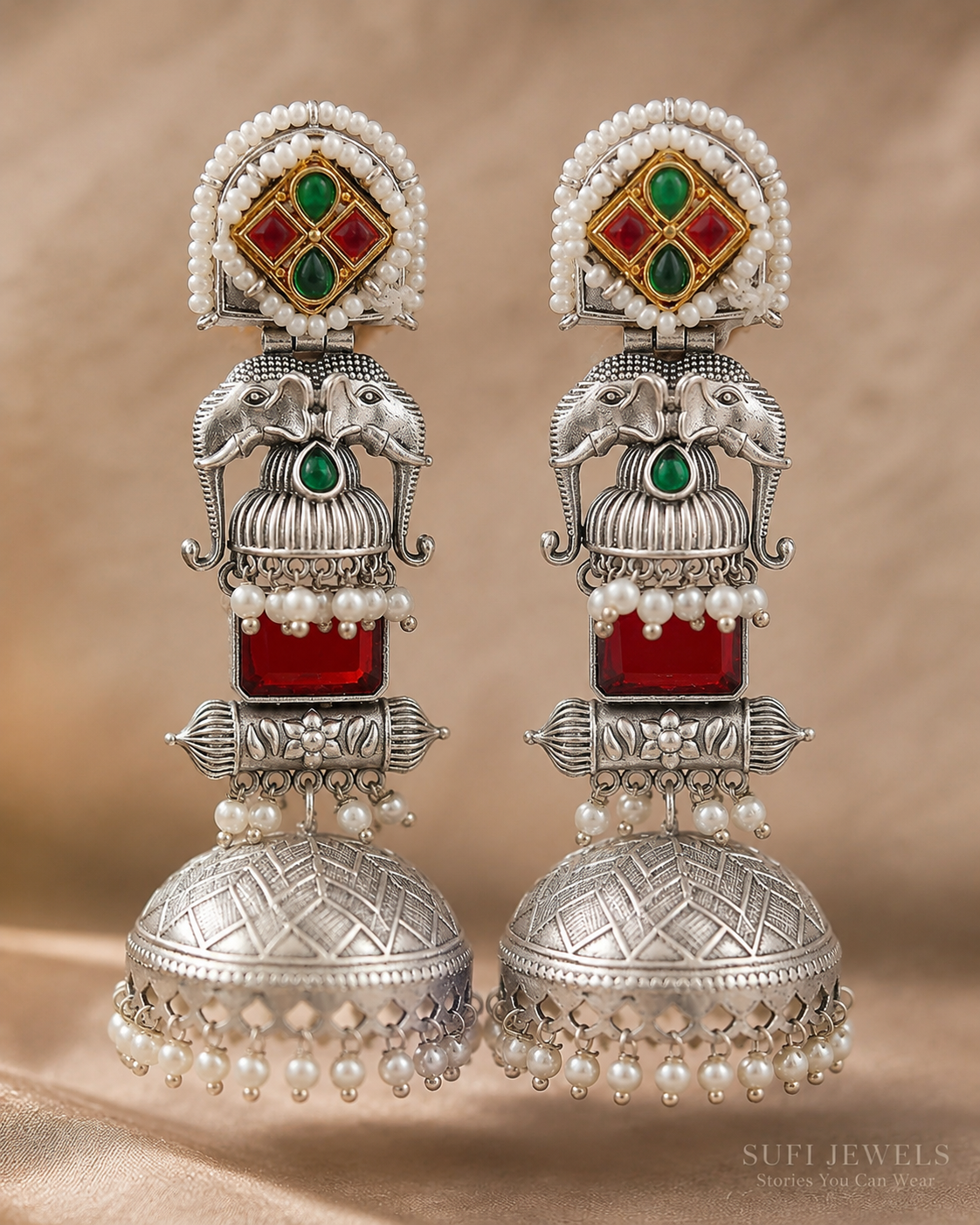 The Temple Between Elephants silver-look jhumki earrings with red and green stones, elephant motifs and white pearl drops.